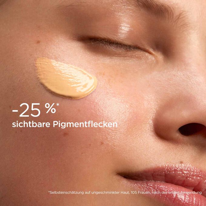 Frau mit Texturklecks des SOS Primer Peach von Clarins auf der Wange, um zu zeigen, dass er Pigmentflecken um 25% reduziert.