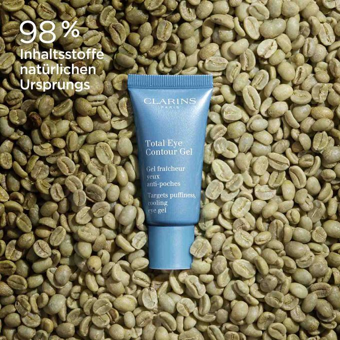 Tube Clarins Total Eye Contour Gel inmitten von Kaffeebohnen,mit Text  98% Inhaltsstoffe natürlichen Ursprungs