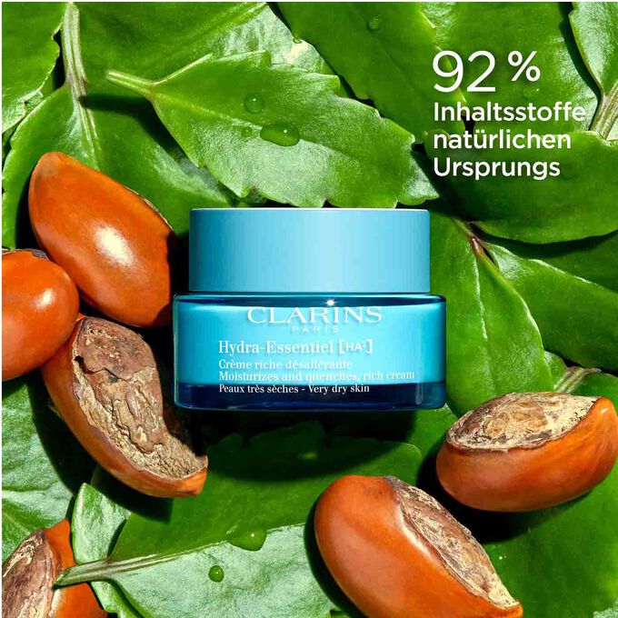 Clarins Crème riche désaltérante inmitten von Blättern und Sheanüssen und Text 92% Inhaltsstoffe sind natürlichen Ursprungs