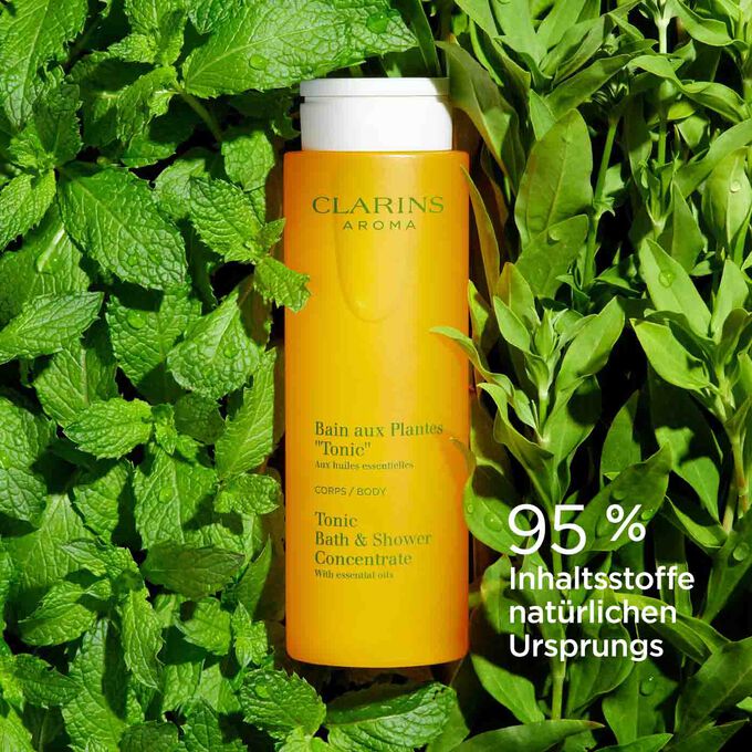 Flakon Clarins Bain Tonic auf Minz- und Rosmarinblättern mit Textinfo, dass 95% Inhaltsstoffe natürlichen  Ursprungs sind