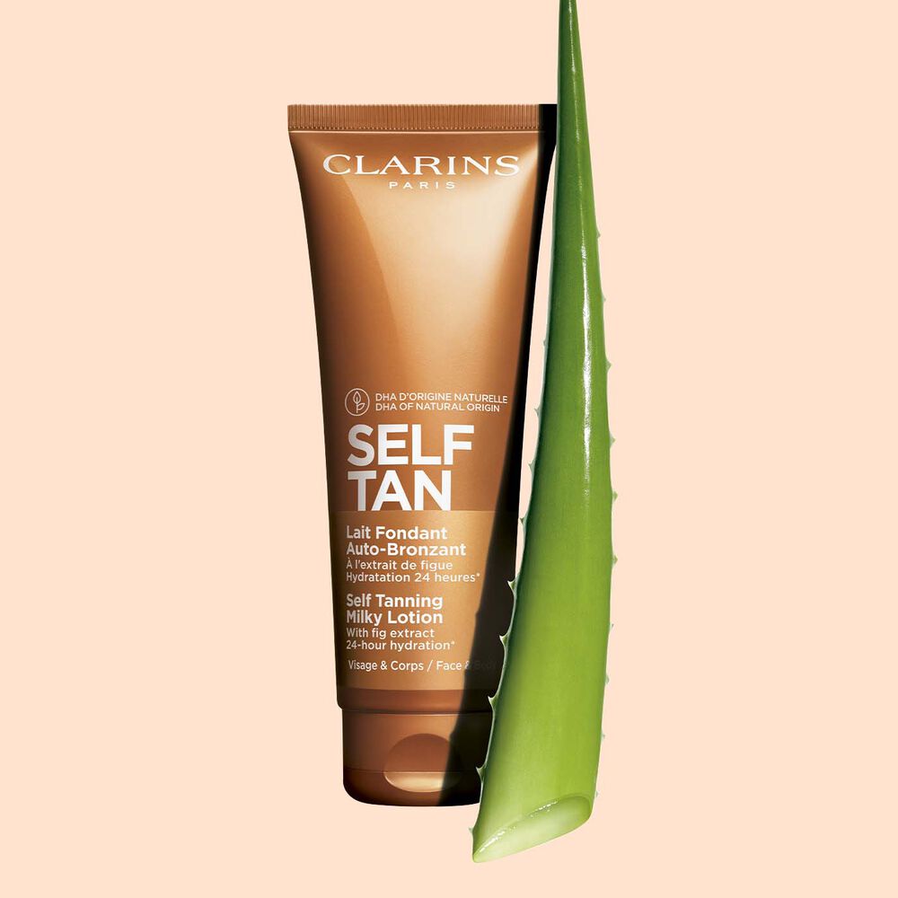 Tube Clarins Lait Fondant Auto-Bronzant Selbstbräumermilch mit einem Stück Aloe vera auf blassorangen Hintergrund