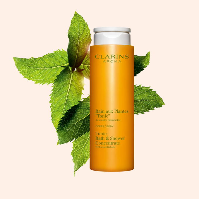 Clarins Bain Tonic Badeschaum und Duschgel mit Ackerminze und Seifenkraut auf orangefarbenem Hingergrund