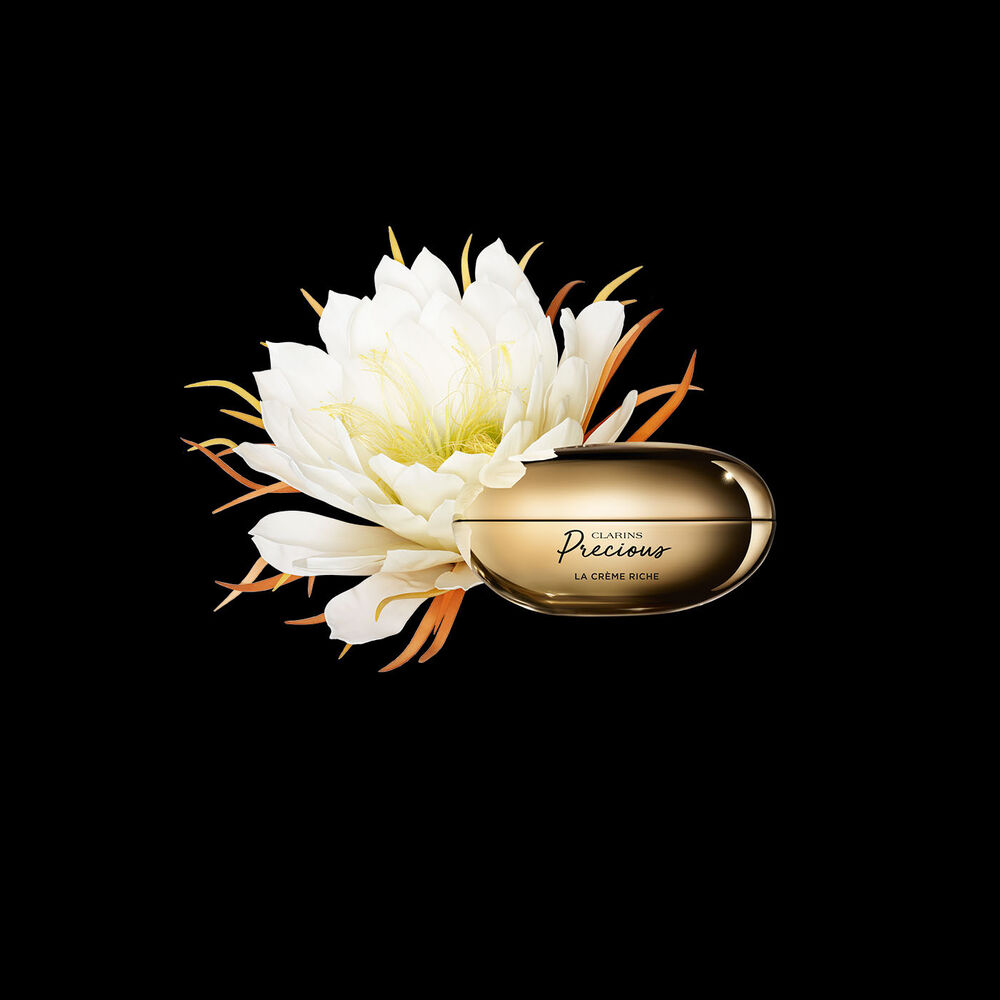 Clarins Precious La Crème Riche vor der Blüte der Königin der Nacht auf schwarzem Hintergrund