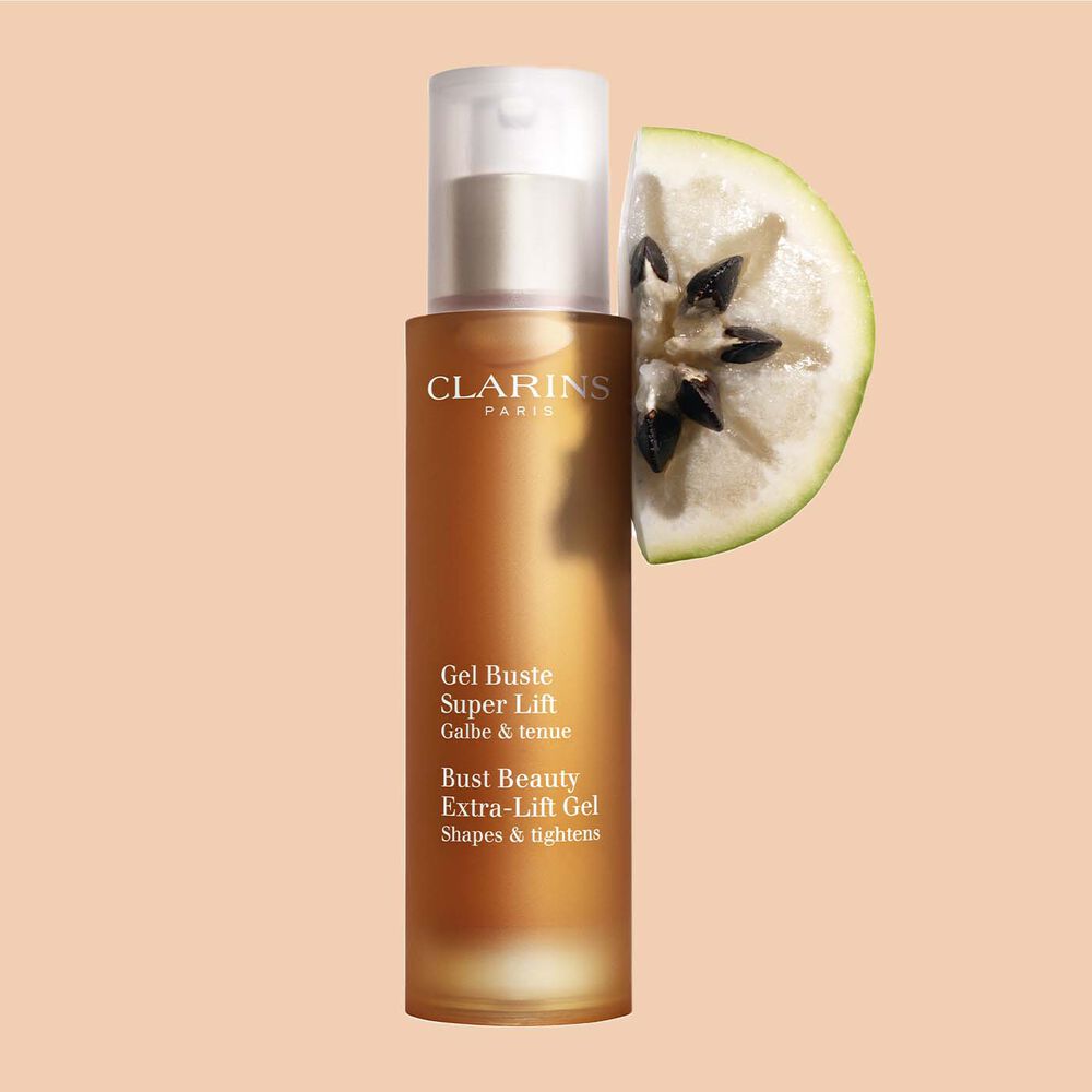 Flakon Clarins Gel Buste Büstenpflege-Gel mit einer Scheibe der Vu Sua Frucht auf einem pfirsichfarbenem Hintergrund.