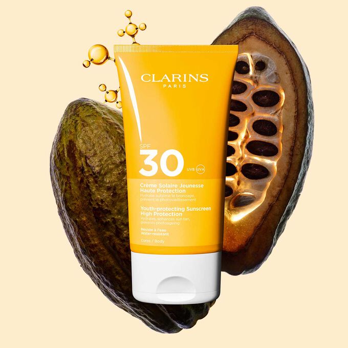 Tube Clarins Cr&egrave;me Solaire Jeunesse SPF 30 f&uuml;r den K&ouml;rper, zwischen Kollagenmolek&uuml;len und Kakaobohnen.