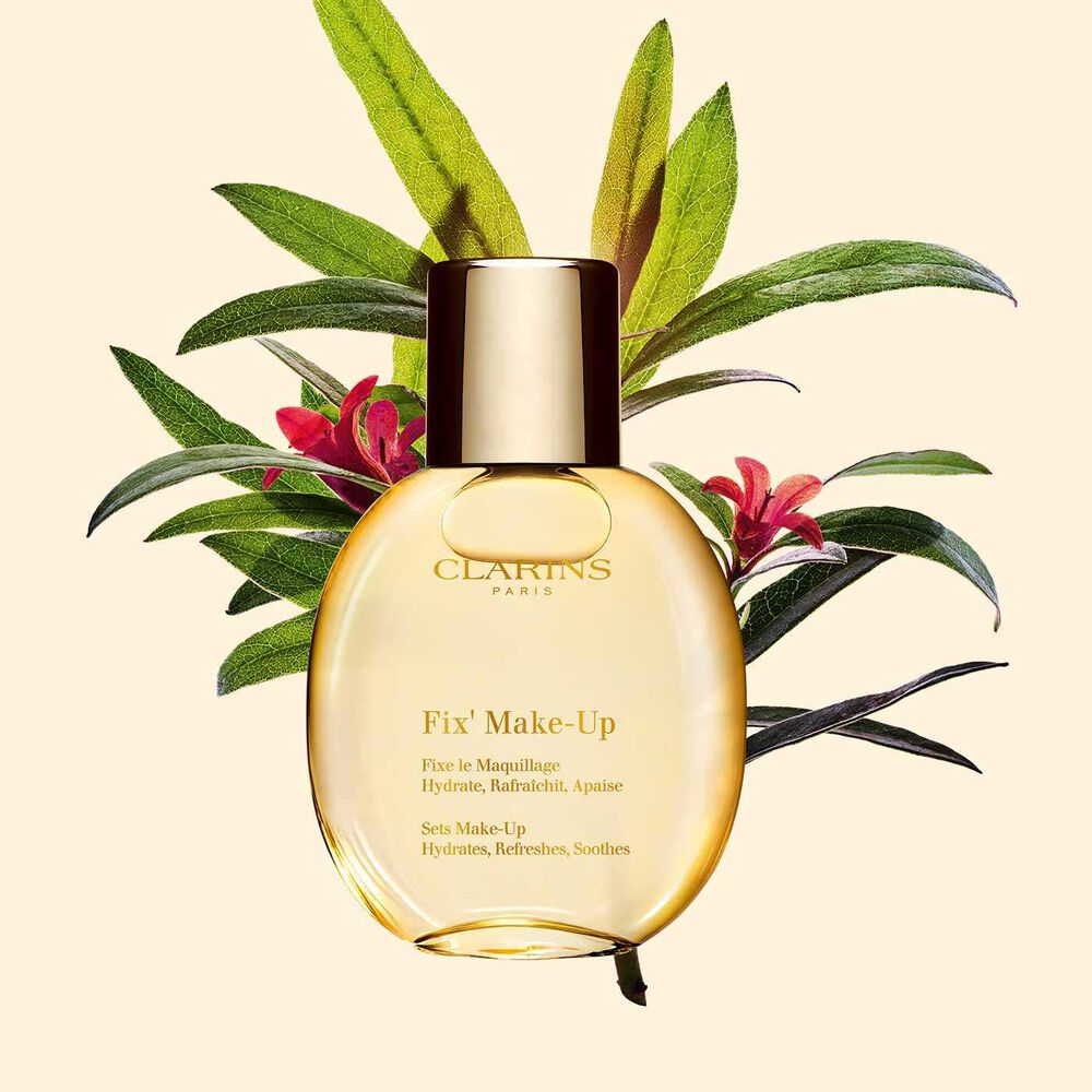 Flakon Clarins Make-up Fixer Spray Fix' Make Up neben einem Strauß Alpenrosen auf einem hellgelben Hintergrund