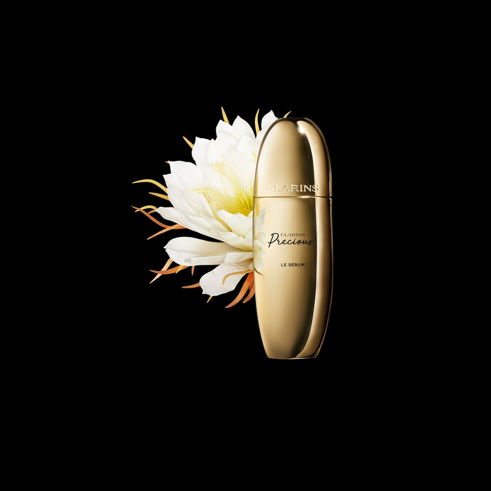 Clarins Precious Le Sérum vor der Blüte der Königin der Nacht auf schwarzem Hintergrund