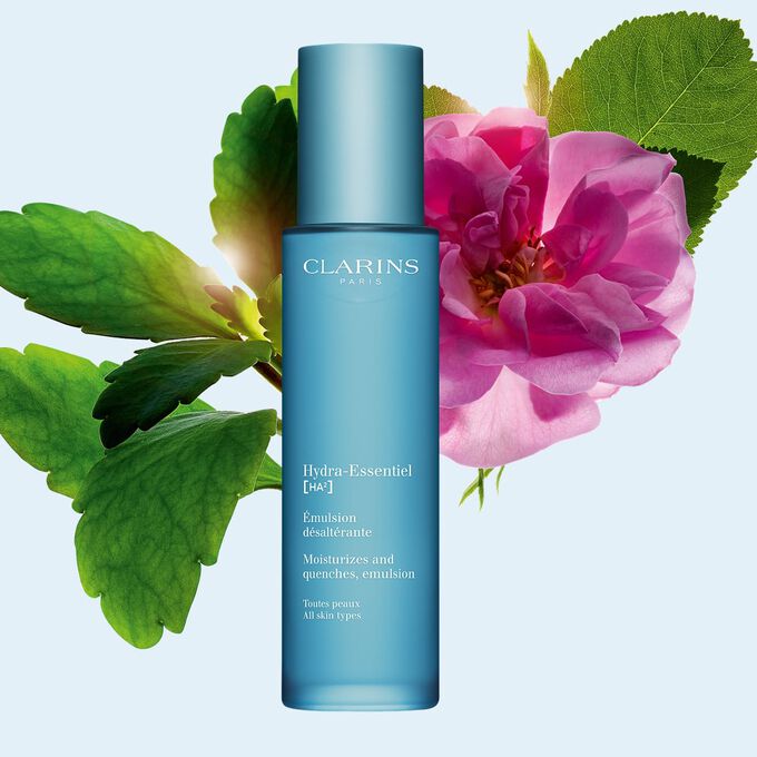Clarins Hydra-Essentiel Emulsion d&eacute;salt&eacute;rante inmitten Damaszener Rose und Goethe-Pflanze auf blauem Hintergrund