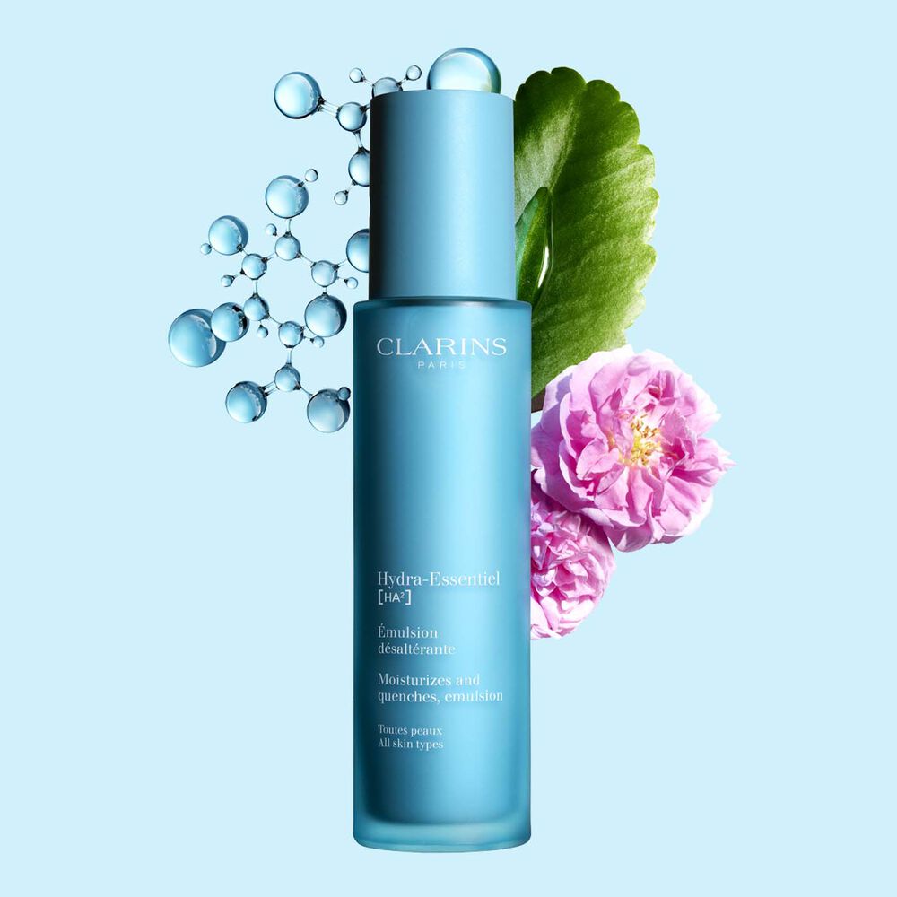 Clarins Hydra-Essentiel Emulsion désaltérante inmitten Damaszener Rose und Goethe-Pflanze auf blauem Hintergrund