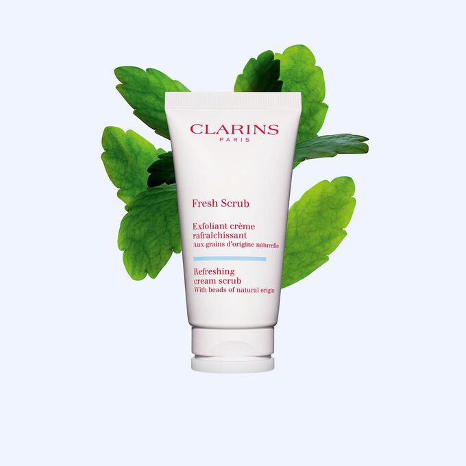 Tube des Gesichtspeelings Fresh Scrub von Clarins vor einem Blatt der Goethe-Pflanze auf wei&szlig;em Hintergrund.