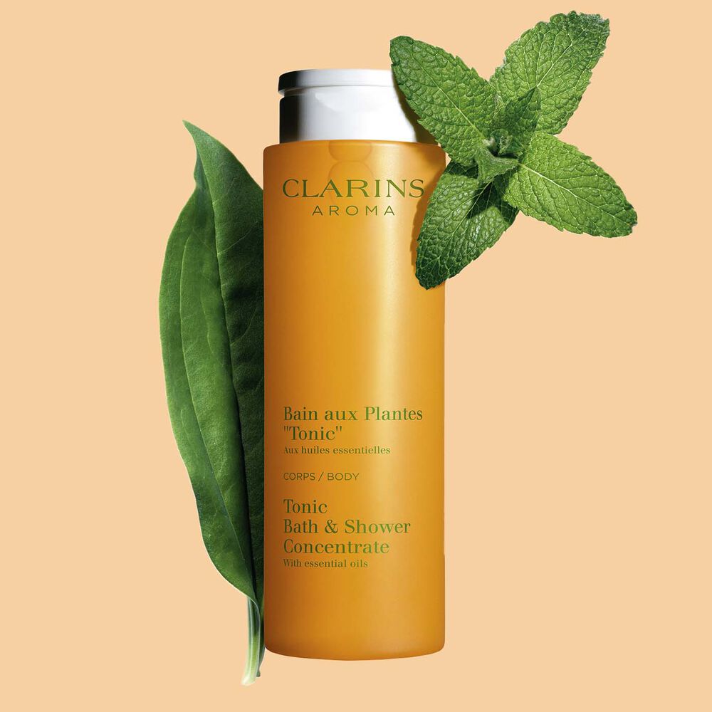 Clarins Bain Tonic Badeschaum und Duschgel mit Ackerminze und Seifenkraut auf orangefarbenem Hingergrund