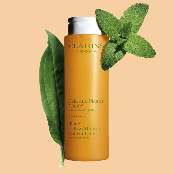 Clarins Bain Tonic Badeschaum und Duschgel mit Ackerminze und Seifenkraut auf orangefarbenem Hingergrund