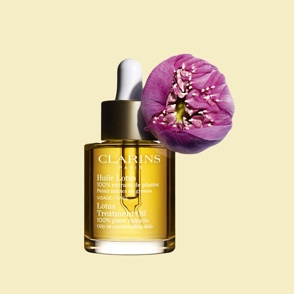 Glasflakon Clarins Gesichtspflegeöl Huile Lotus mit einer Lotusblüte auf blassgelbem Hintergrund.