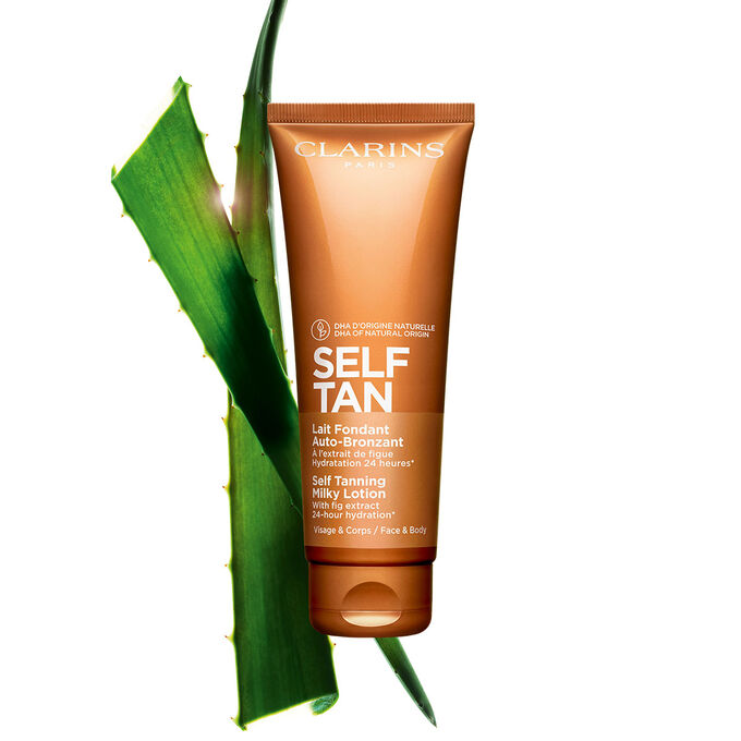 Tube Clarins Lait Fondant Auto-Bronzant Selbstbr&auml;umermilch mit einem St&uuml;ck Aloe vera auf blassorangen Hintergrund
