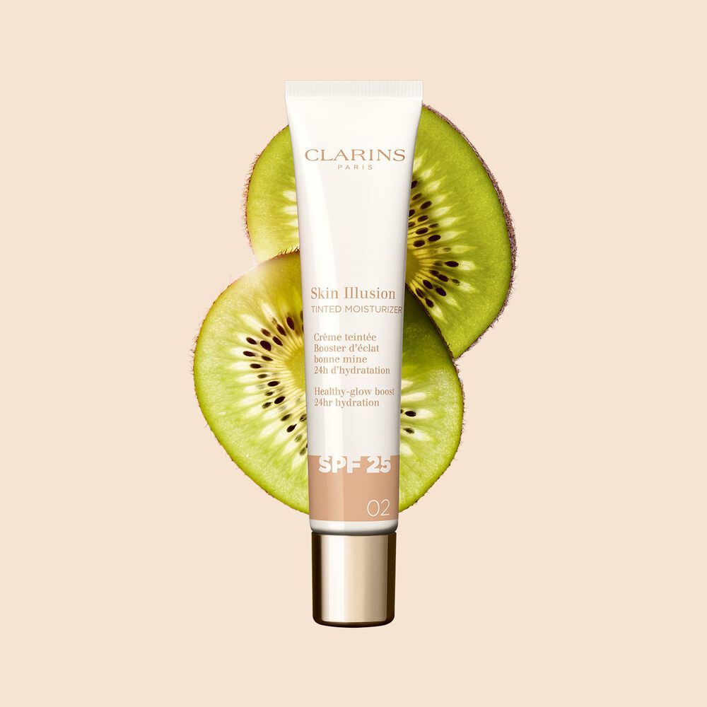 40 ml-Tube des Teint-Perfektionierers Tinted Moisturizer mit SPF, Farbton 02, zwischen Kiwischeiben auf beigem Hintergrund