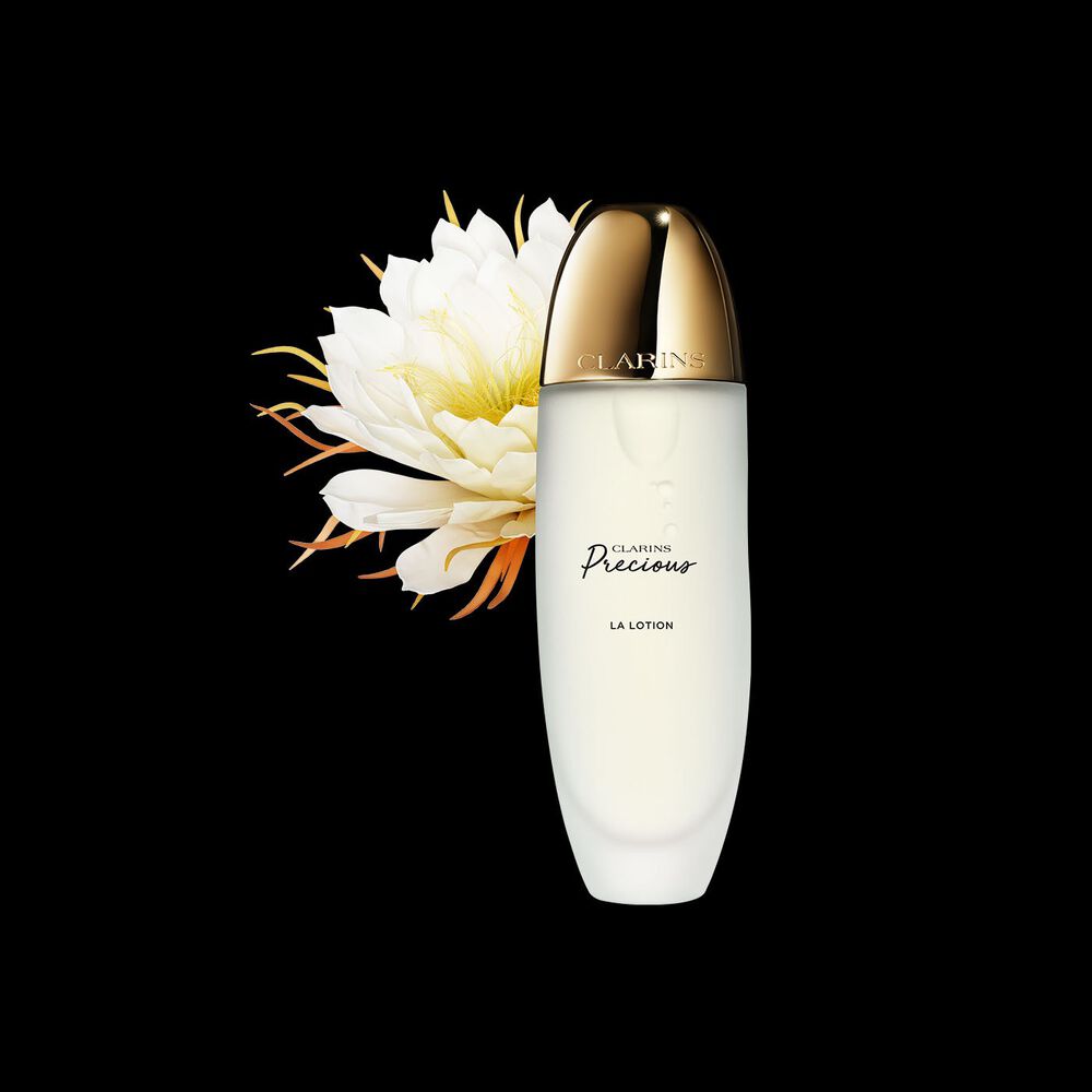 Clarins Precious La Lotion vor der Blüte der Königin der Nacht auf schwarzem Hintergrund