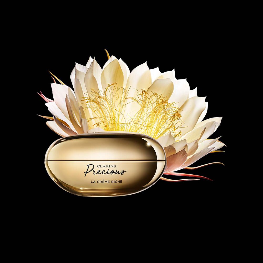 Clarins Precious La Crème Riche vor der Blüte der Königin der Nacht auf schwarzem Hintergrund