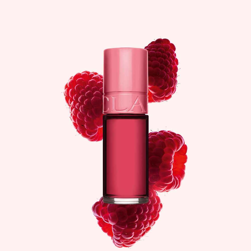 Clarins Lip Stain Shade 11 soft pink water neben Himbeeren auf einem hellrosa Hintergrund.