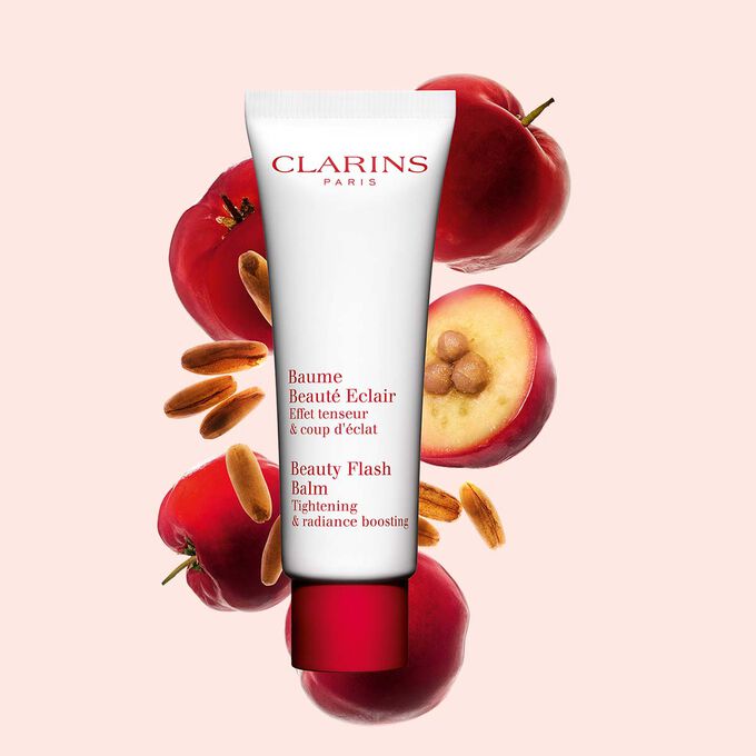 Tube Clarins Baume Beauté Eclair mit Acerolakirschen auf pfirsichfarbenem Hintergrund