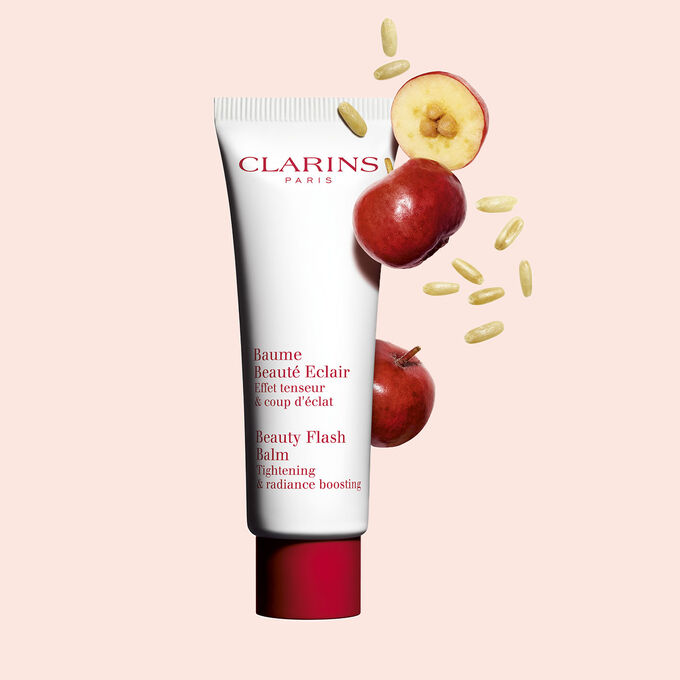 Tube Clarins Baume Beauté Eclair mit Acerolakirschen auf pfirsichfarbenem Hintergrund