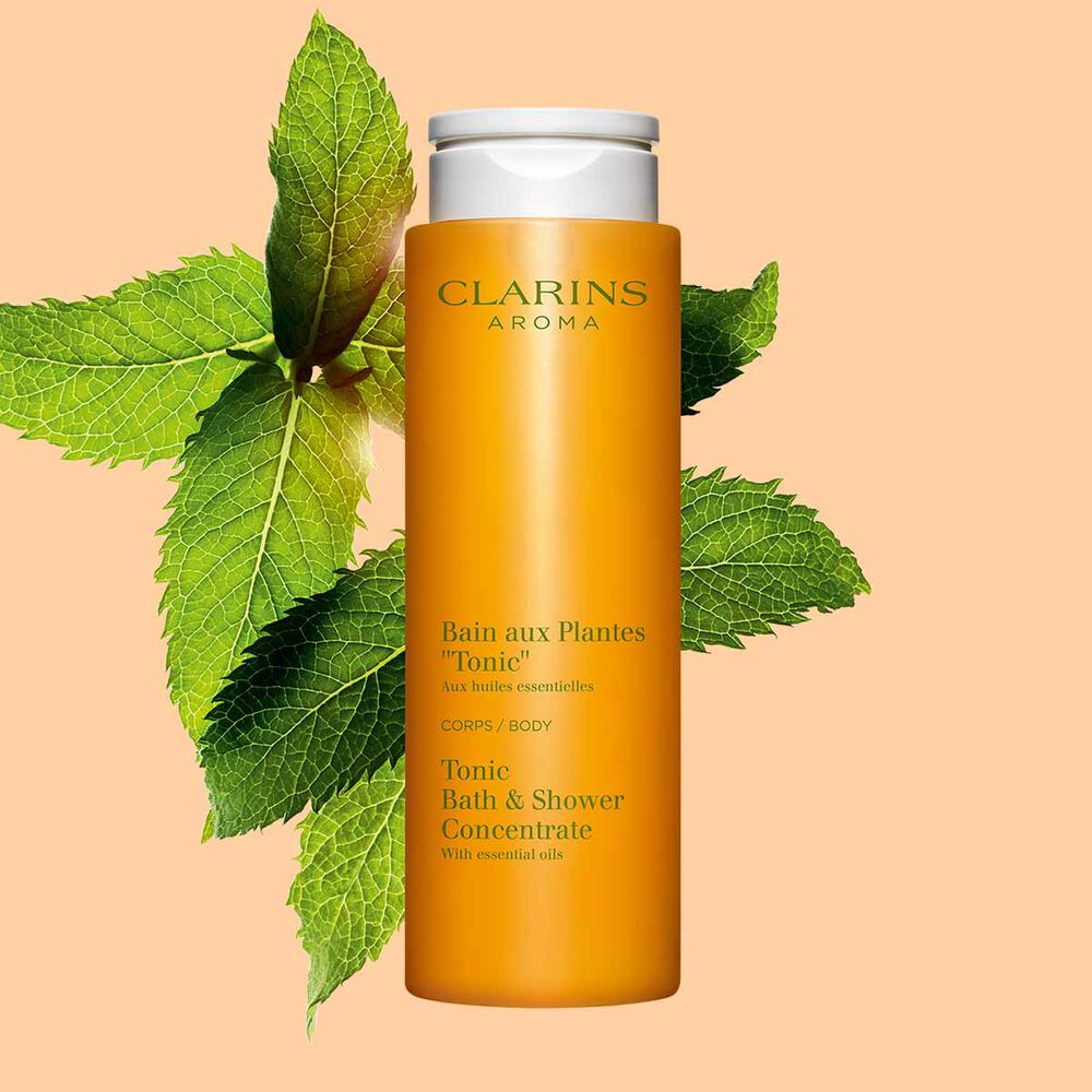 Clarins Bain Tonic Badeschaum und Duschgel mit Ackerminze und Seifenkraut auf orangefarbenem Hingergrund