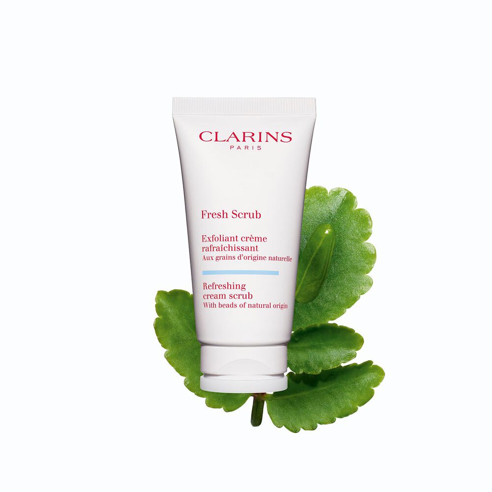 Tube des Gesichtspeelings Fresh Scrub von Clarins vor einem Blatt der Goethe-Pflanze auf weißem Hintergrund.
