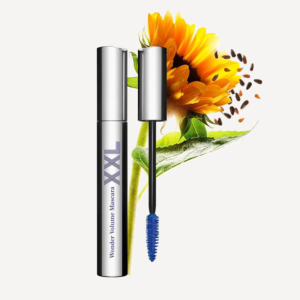 Clarins Wonder Volume Mascara XXL in Blau neben einer Sonnenblume auf einem hellgrauen Hintergrund