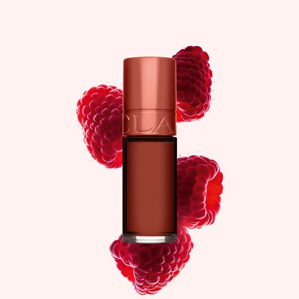 Clarins Lip Stain Shade 13 nude water neben Himbeeren auf einem hellrosa Hintergrund.