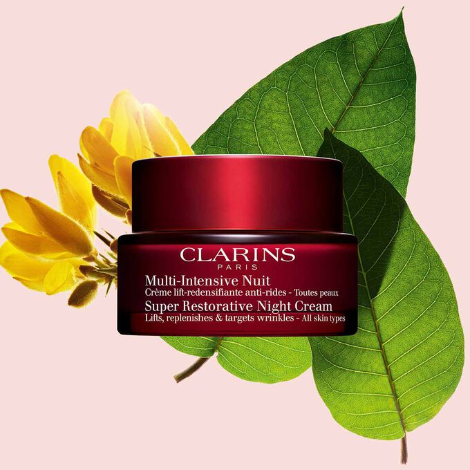 Tiegel Clarins Multi-Intensive Nachtcreme vor Stechginster-Bl&uuml;te und Haronga-Bl&auml;ttern auf rosafarbenem Hintergrund