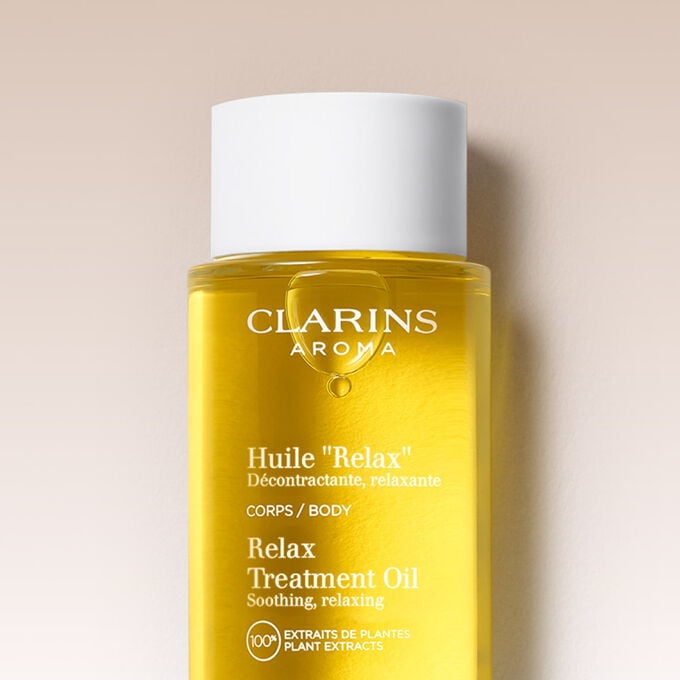 Glasflakon Clarins Huile Relax mit Kamillenbl&uuml;ten, um zu verdeutlichen, dass es zu 100 % aus Pflanzenextrakten besteht