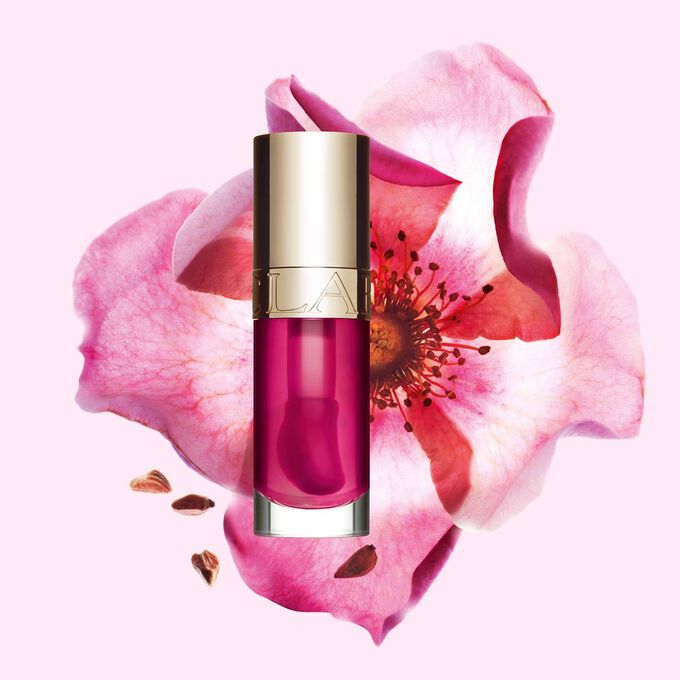 Clarins Lip Comfort Oil 02 Rasberry mit pflegender Wirkung vor einer Weinrose, um die natürlichen Inhaltsstoffe hervorzuheben