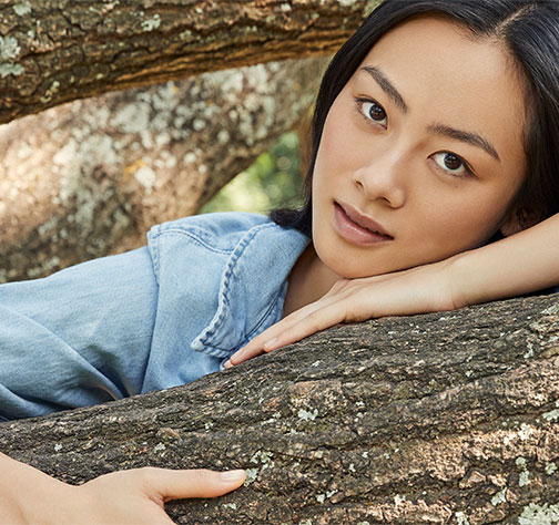 Une femme est accoudée à une branche d'arbre