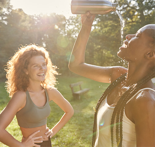 2 junge Frauen, die Wasser trinken und lachen